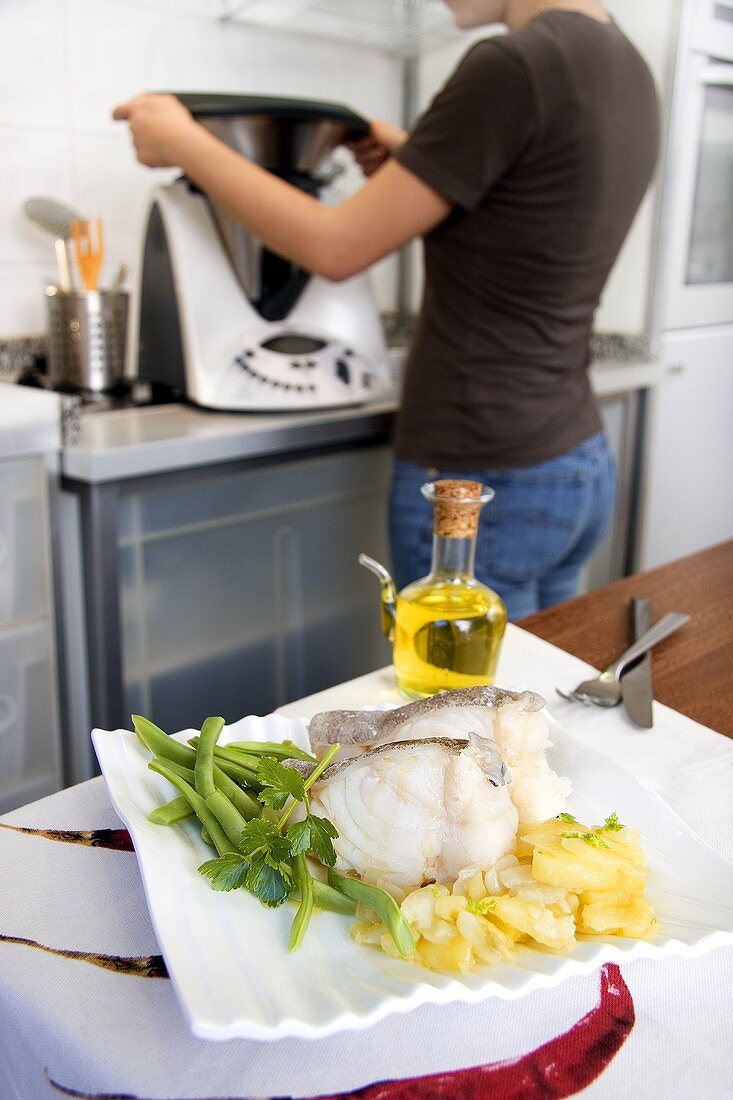 Cod with potatoes and green beans on kitchen table