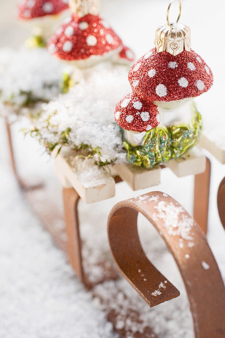 Christbaumschmuck (Fliegenpilze) auf kleinem Schlitten