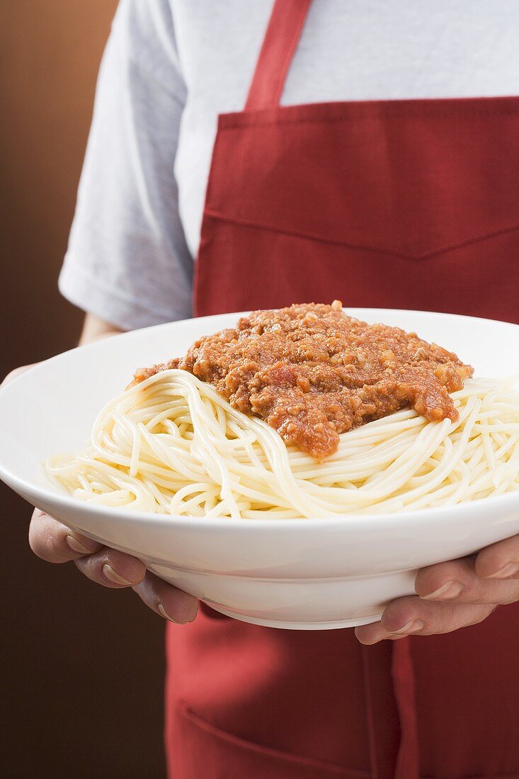 Person serviert Spaghetti Bolognese