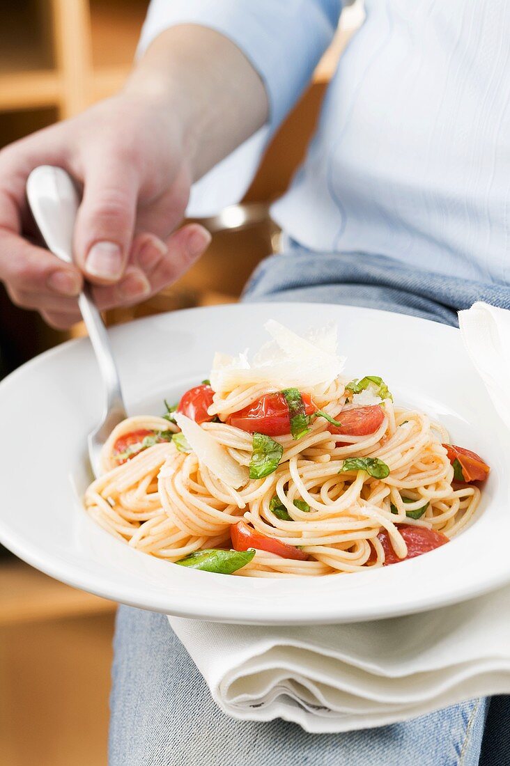 Person isst Spaghetti mit Tomaten