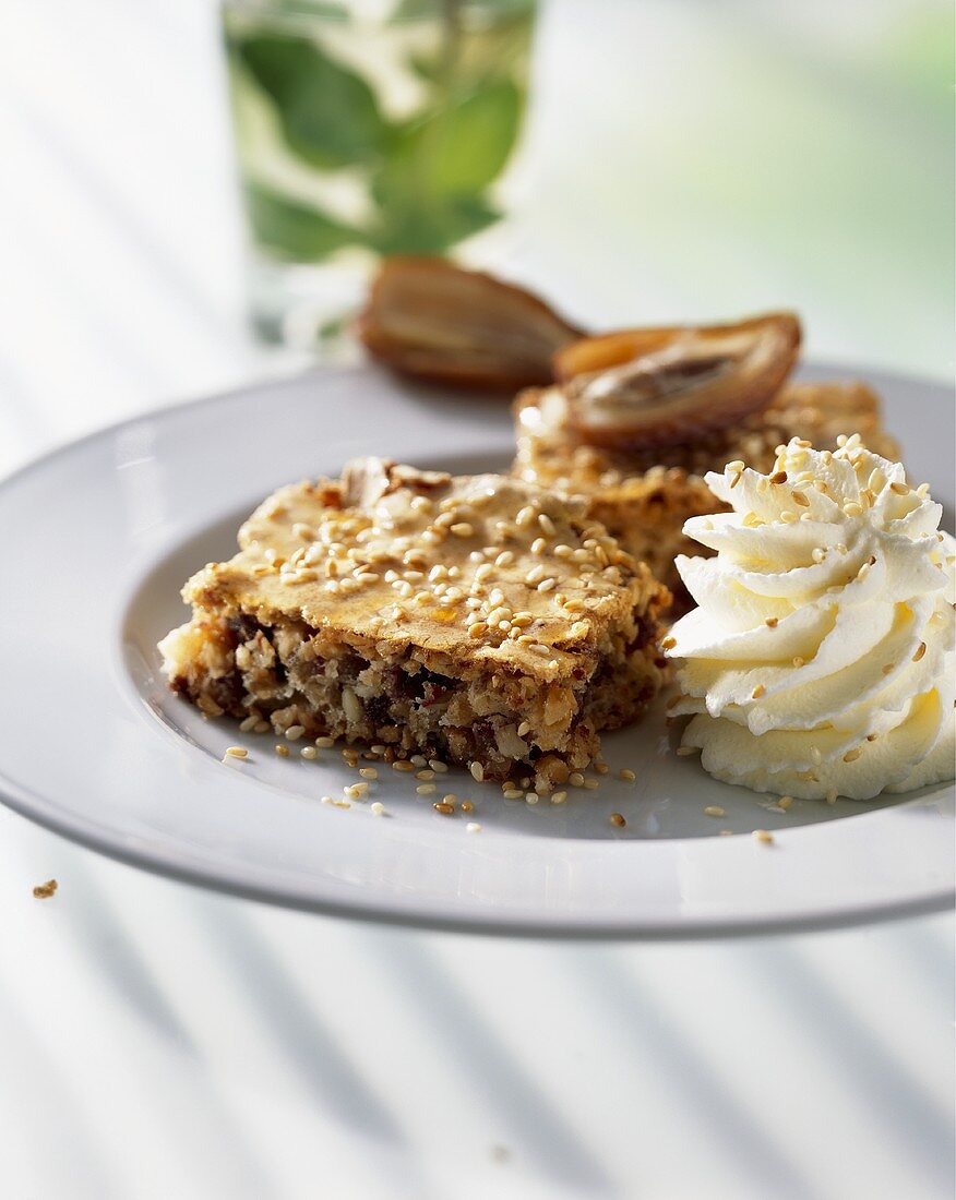 Piece of date tart with sesame seeds and cream