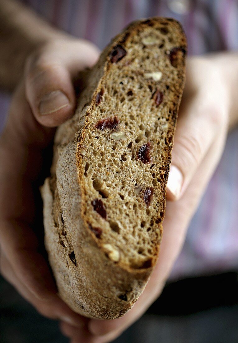 Hands holding nut bread with a piece cut off