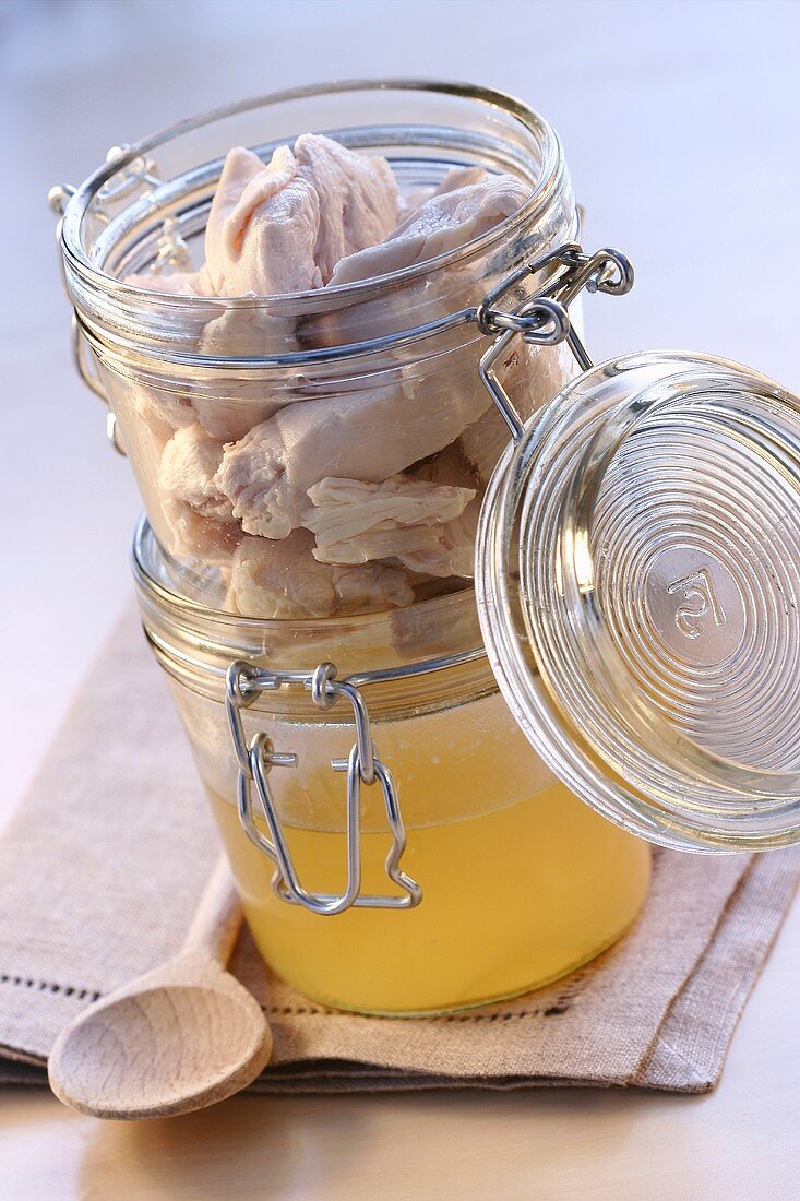 Clear chicken stock and chicken breast in jars