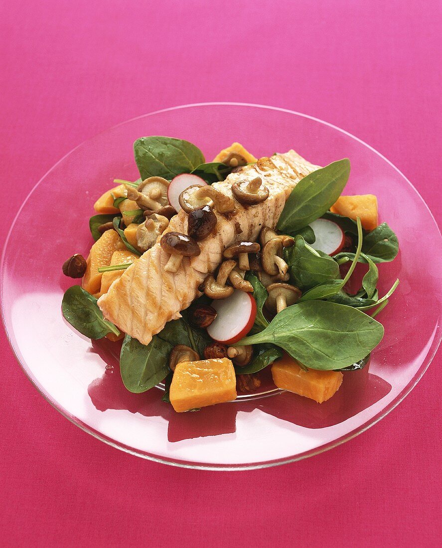 Spinach salad with mushrooms and fried salmon fillet