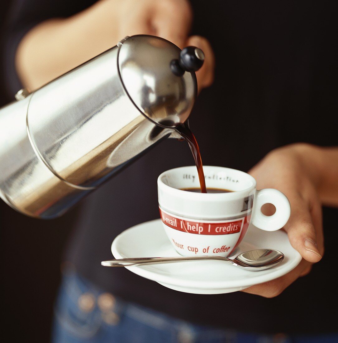 Pouring espresso into a cup from a pot