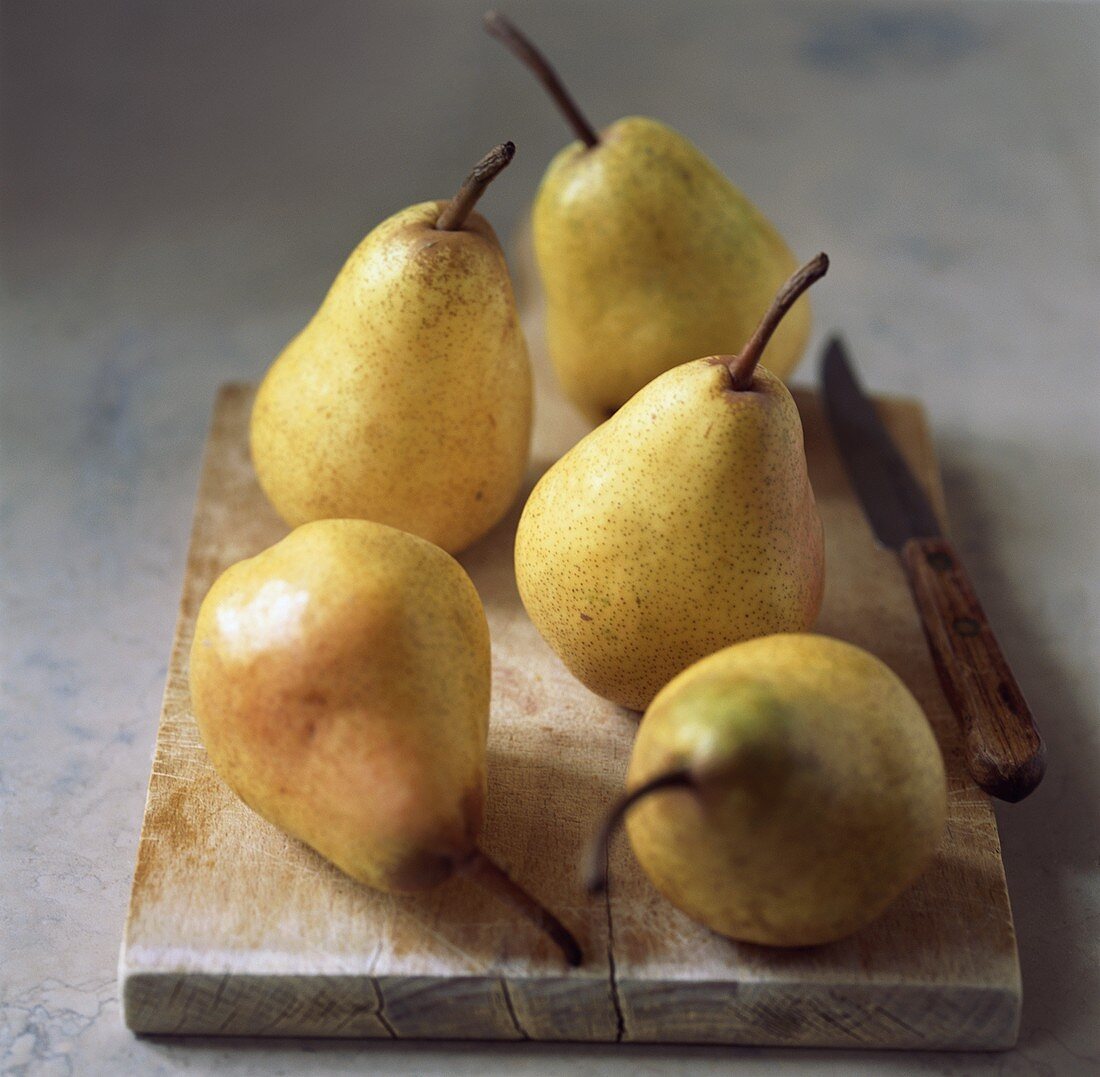 Five yellow pears on a chopping board