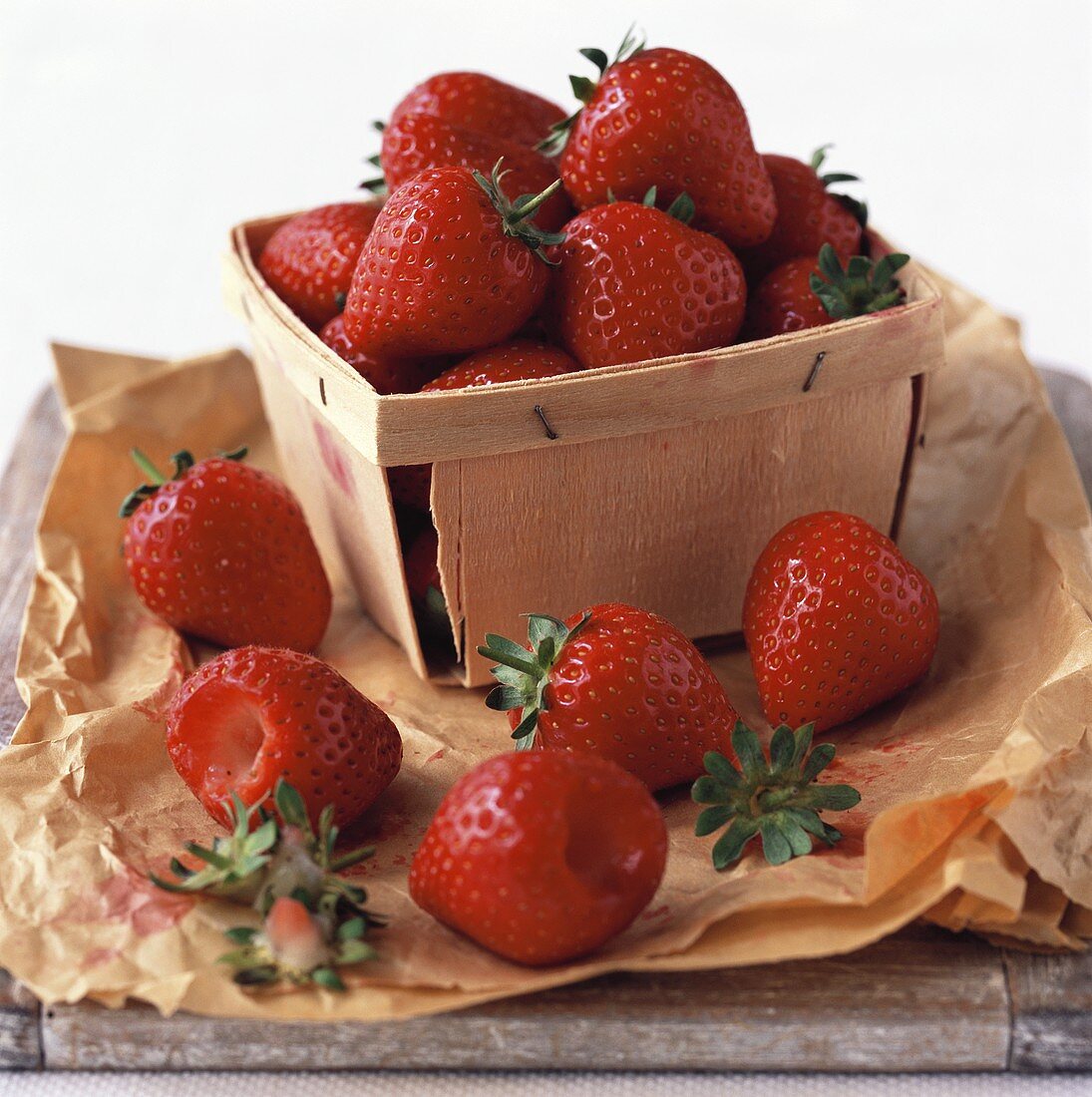 Erdbeeren im Spankorb und daneben auf Papier