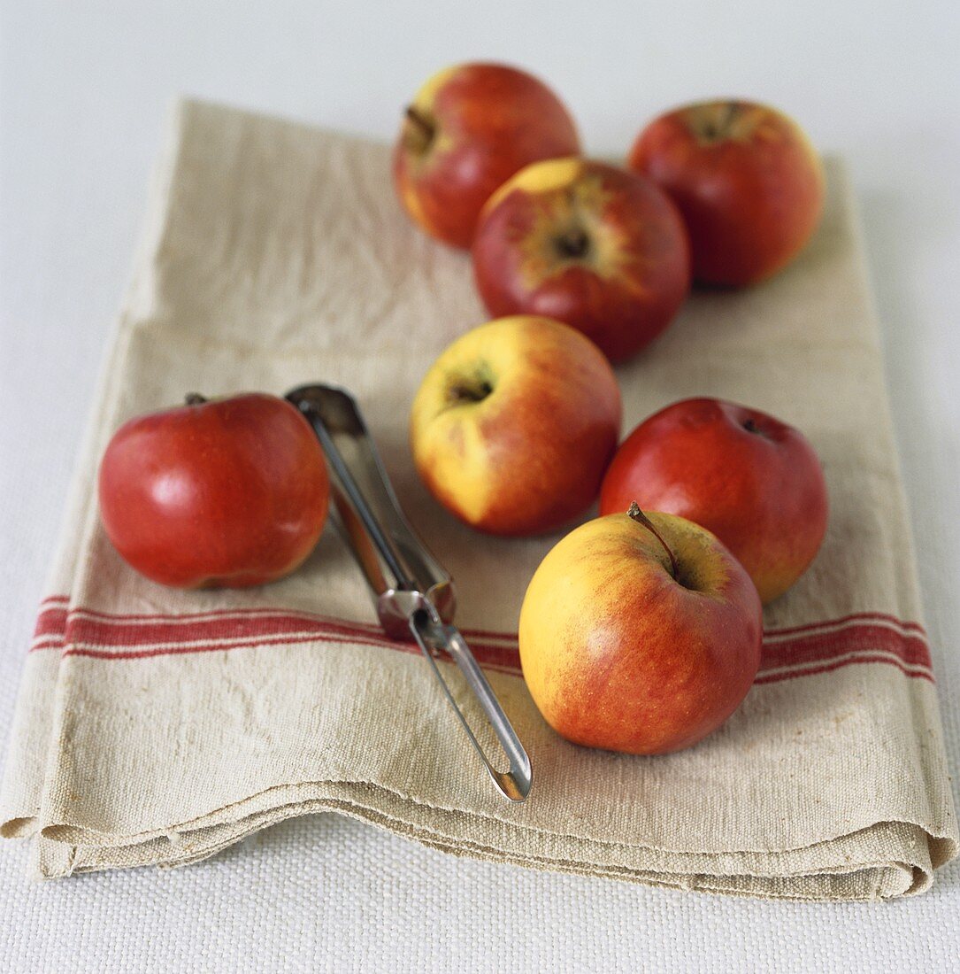 Fresh apples on linen cloth with peeler
