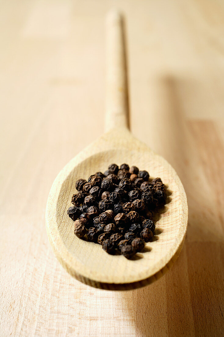 Peppercorns on wooden spoon