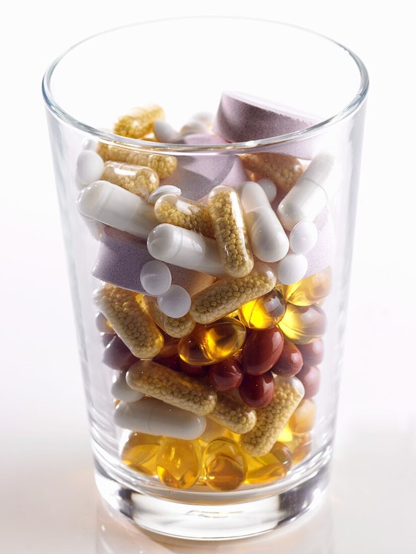 Assorted capsules and tablets in a glass