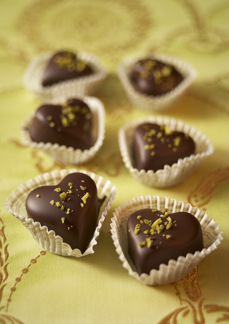 Heart-shaped chocolates with chopped pistachios in sweet cases
