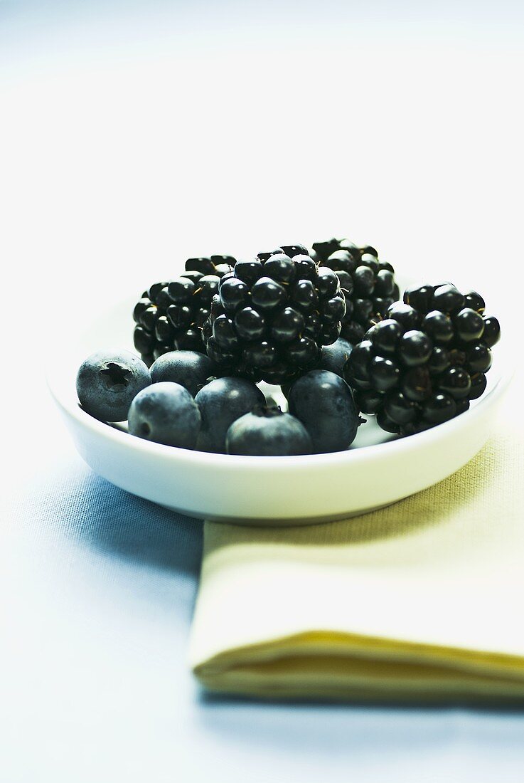 Blueberries and blackberries in a white dish