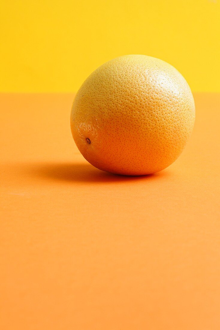 A grapefruit on an orange background
