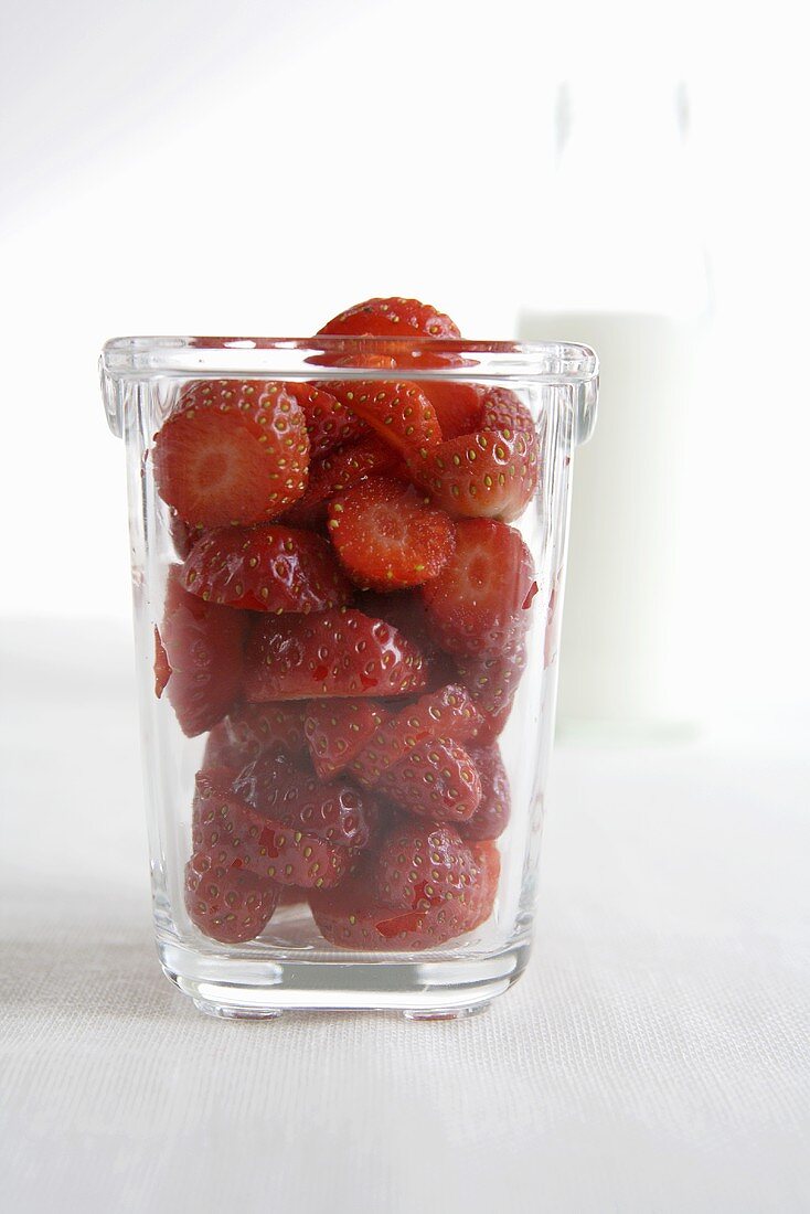 Fresh strawberries in a glass in front of milk bottle
