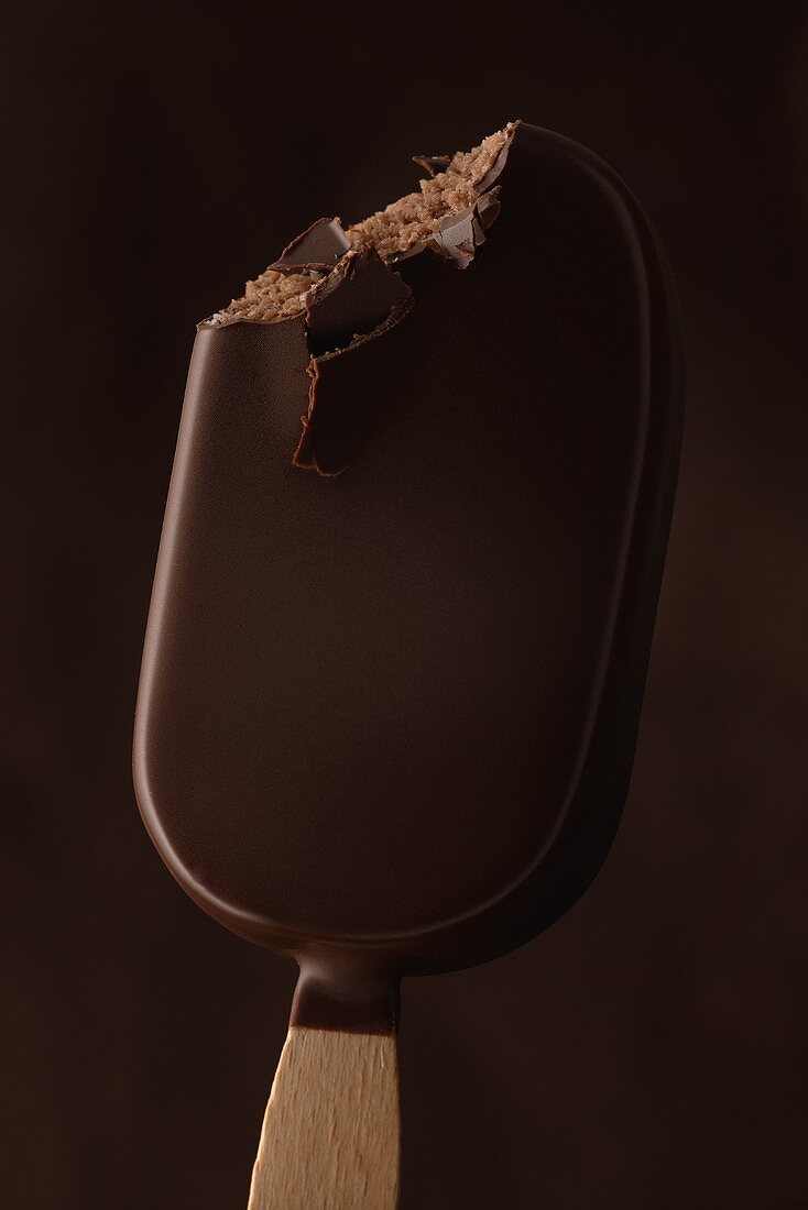 Chocolate-coated ice cream on a stick, a bite taken