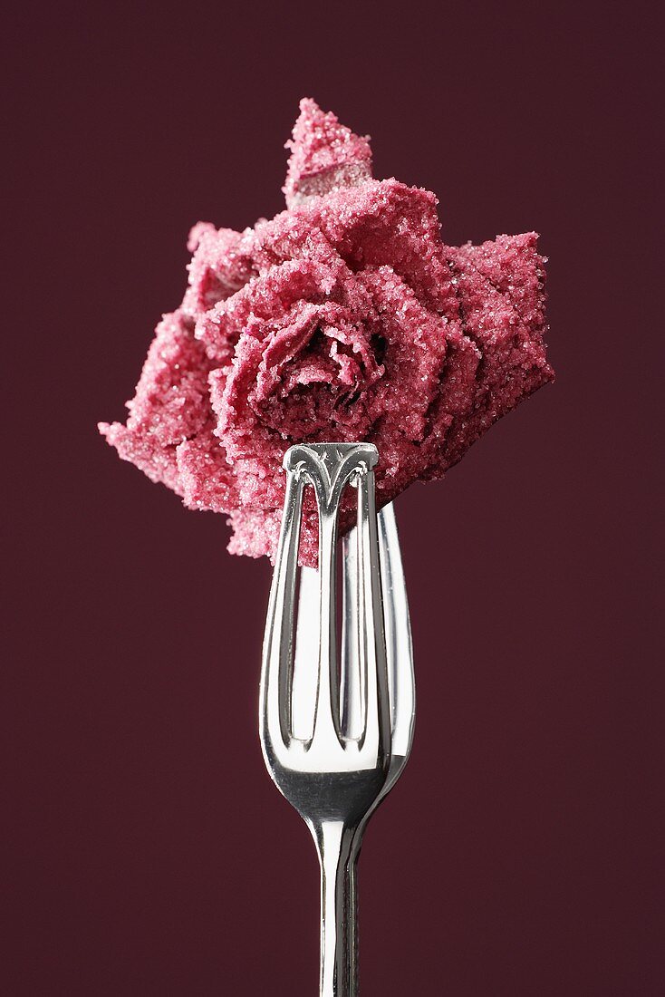 Candied rose held in tongs