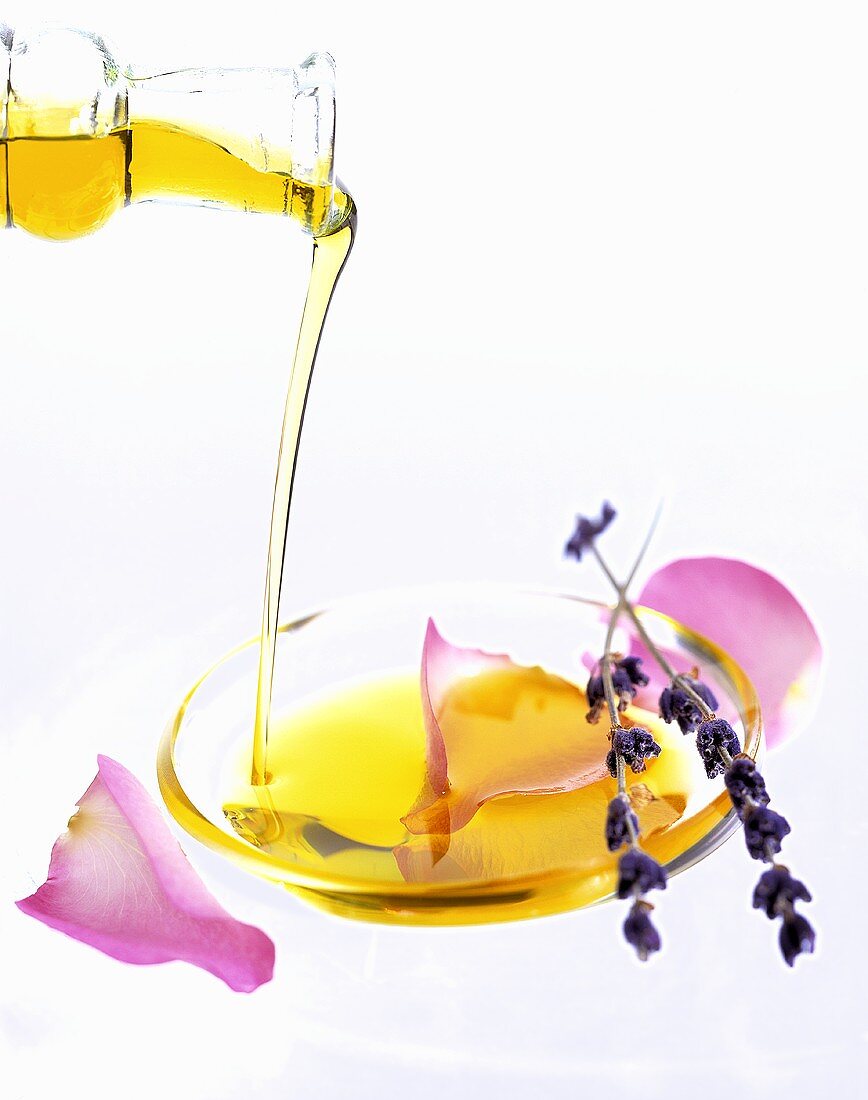Pouring oil into a dish with rose petals and lavender
