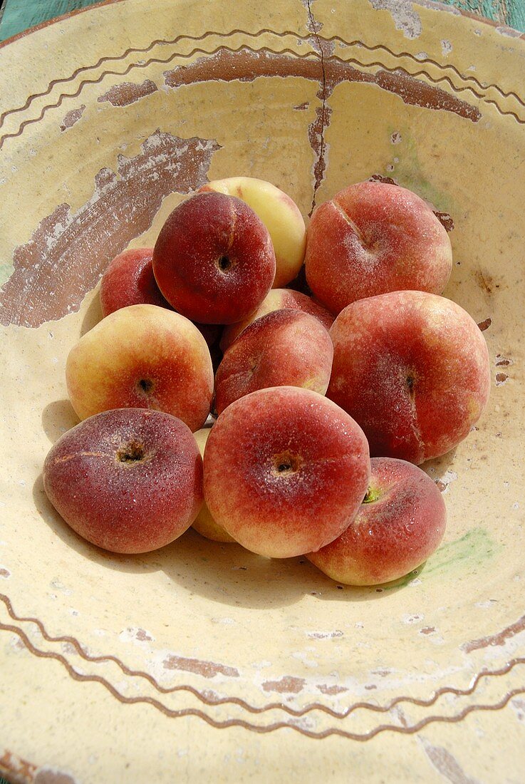 Fresh vineyard peaches in bowl (overhead view)