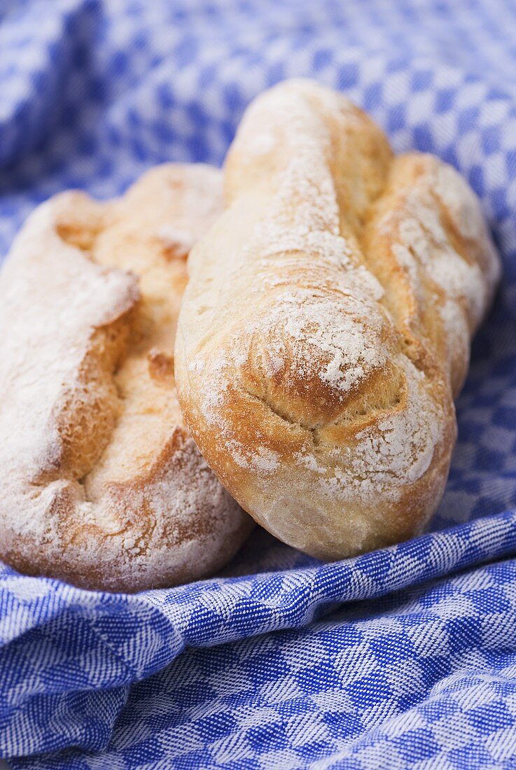 Two ciabatta loaves on tea towel