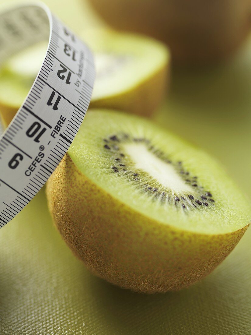 Two halves of a kiwi fruit with tape measure
