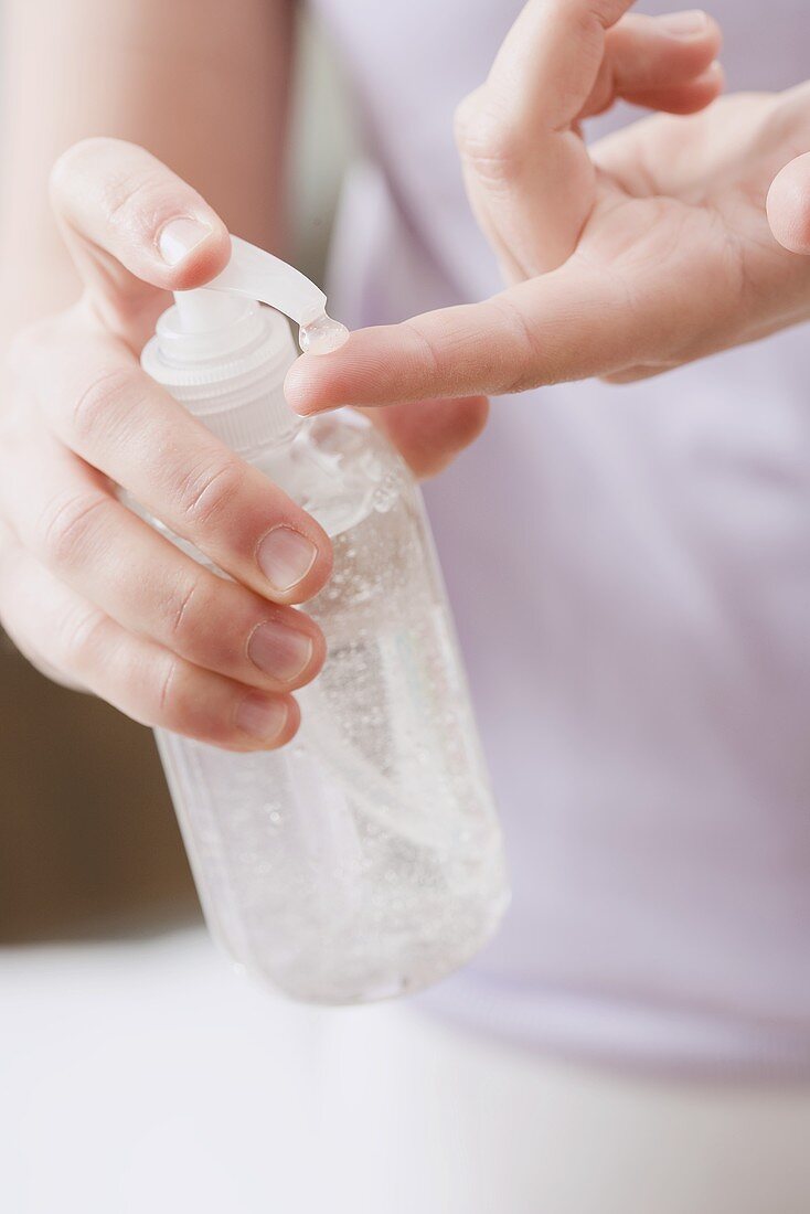 Frau drückt Gel aus Flasche auf ihren Finger