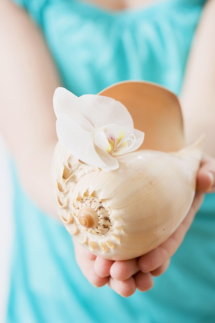 Woman holding shell with orchid