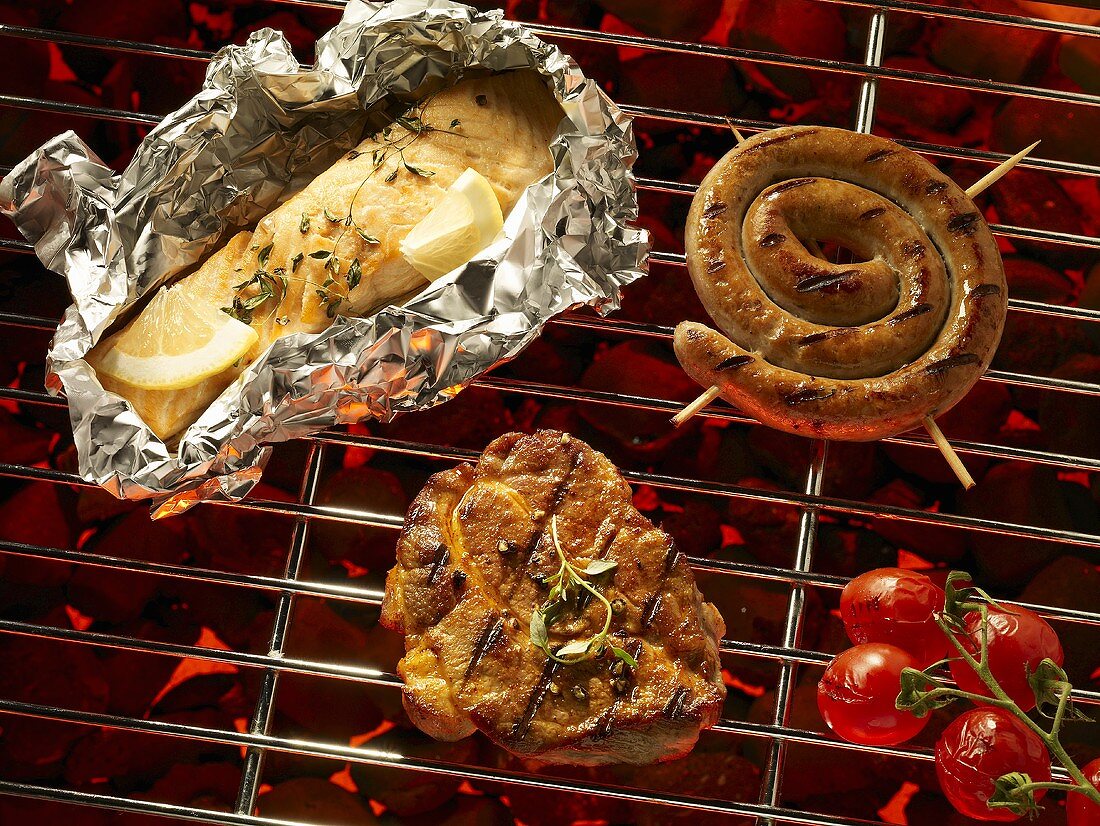 Fish in foil, meat, sausage and tomatoes on a barbecue