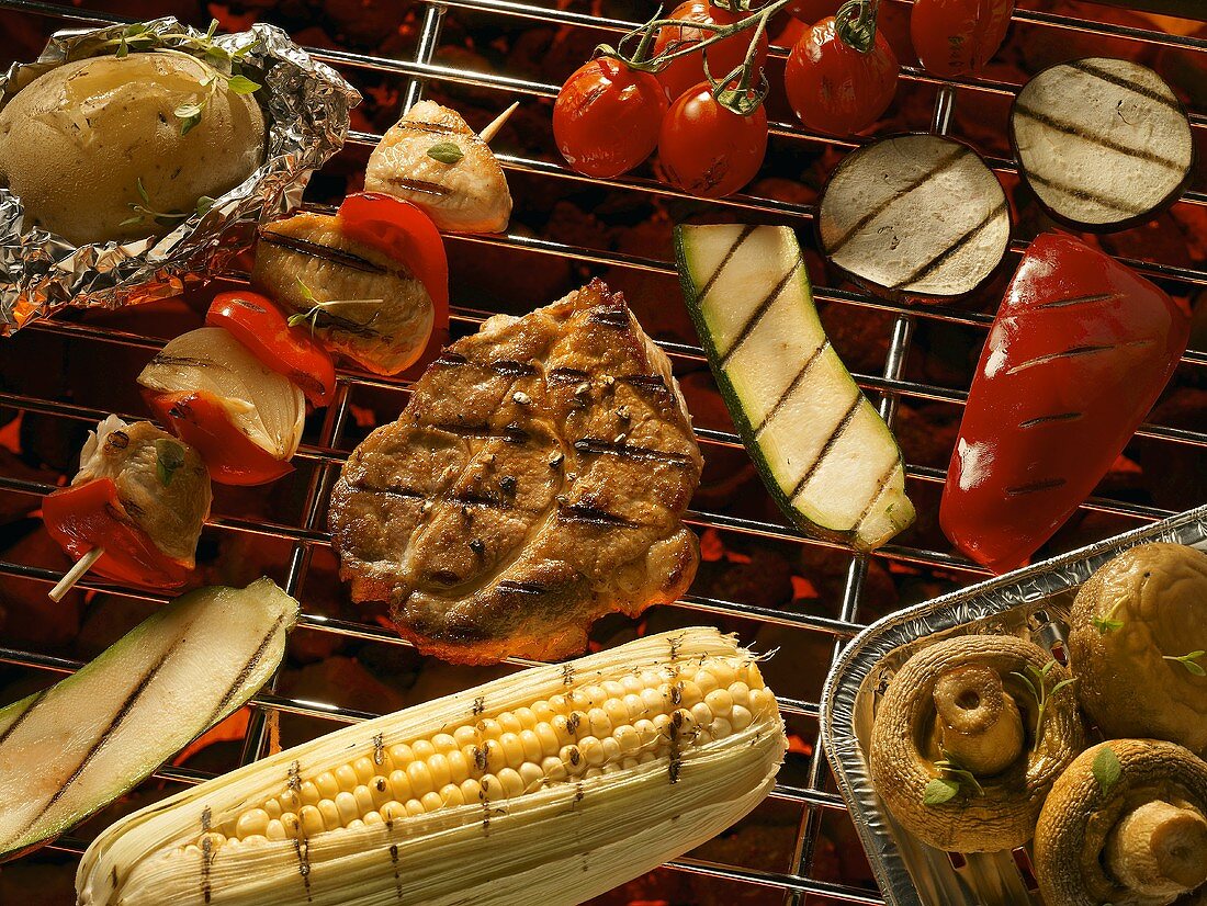 Vegetables, meat, mushrooms & corn on the cob on a barbecue