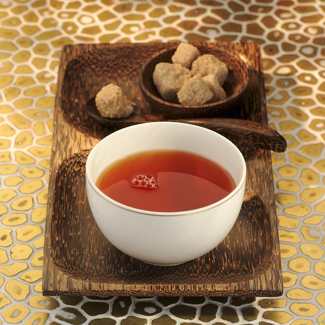 Rooibos tea in white bowl, brown sugar cubes behind