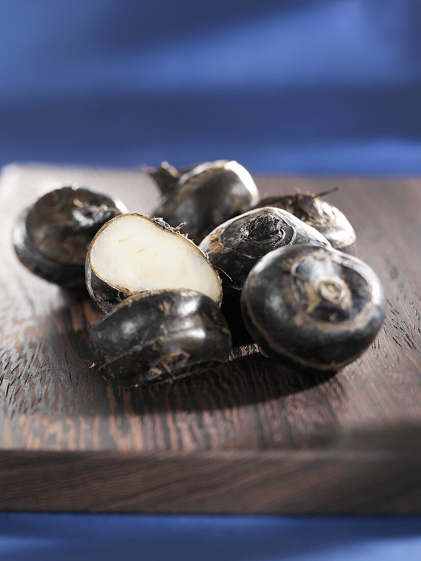 Water chestnuts, whole and halved, on wooden board
