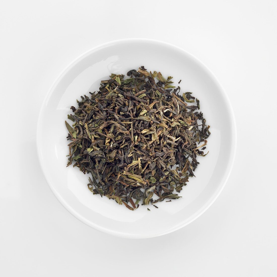 Organic Darjeeling tea leaves in dish (overhead view)