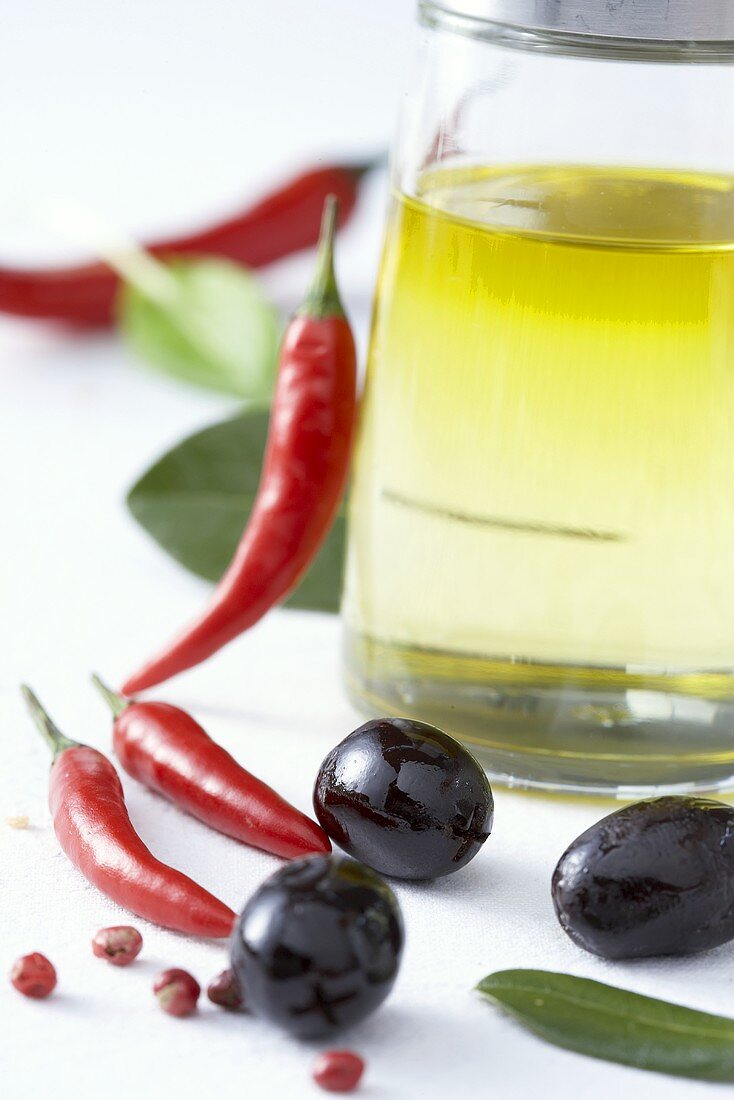 Olivenöl, Chilischoten, schwarze Oliven und Pfefferkörner