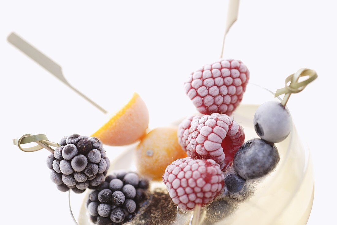 Frozen fruit skewers in a saucer of champagne