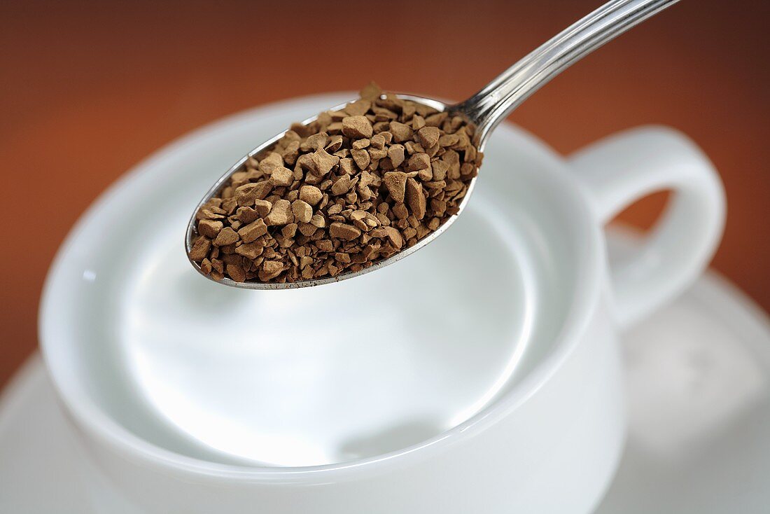 Löslicher Kaffee auf Löffel über Tasse