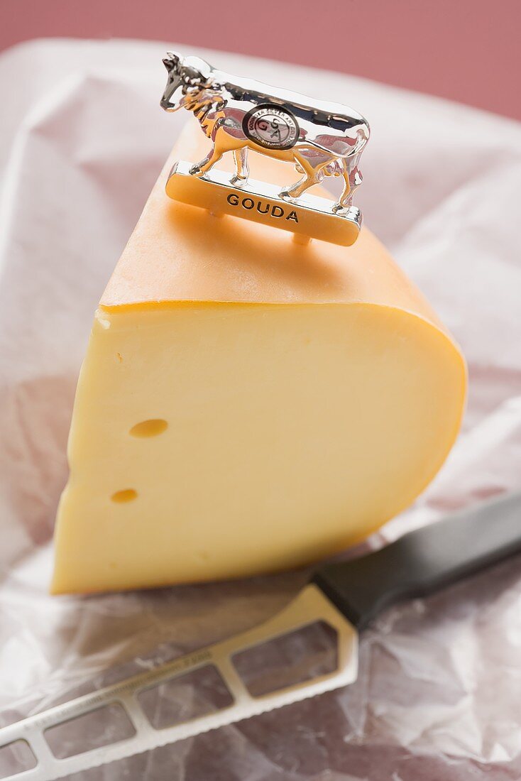 Piece of Gouda cheese with label and cheese knife