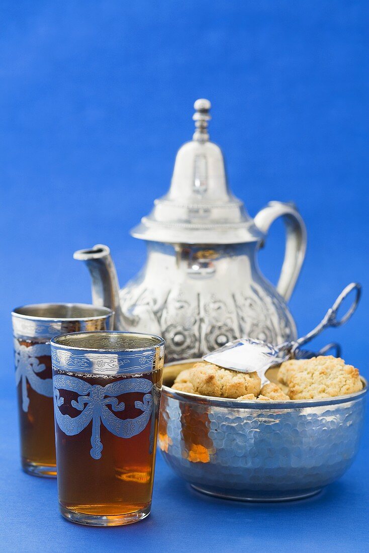 Two glasses of black tea, biscuits and silver teapot