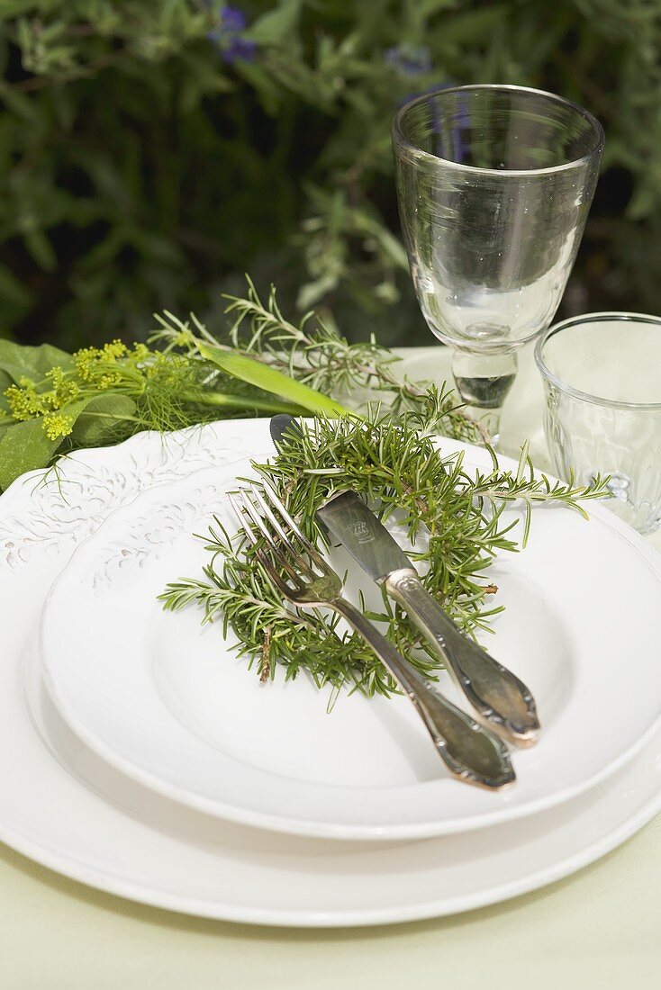 Place-setting with rosemary on table in garden