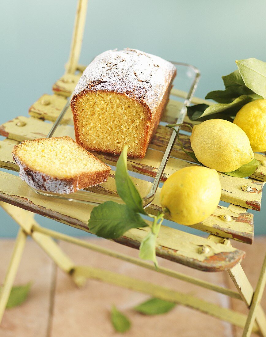 Zitronenkuchen und frische Zitronen auf Gartenstuhl