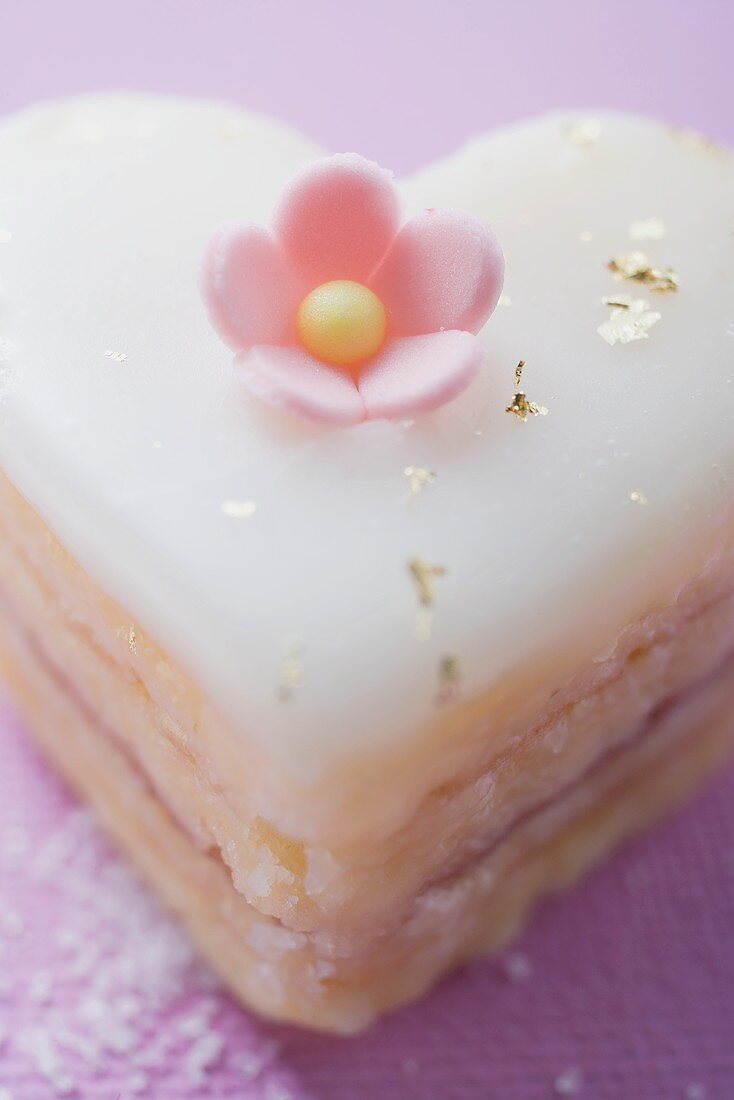 Herzförmiges Törtchen mit Zuckerblüte und Goldflocken