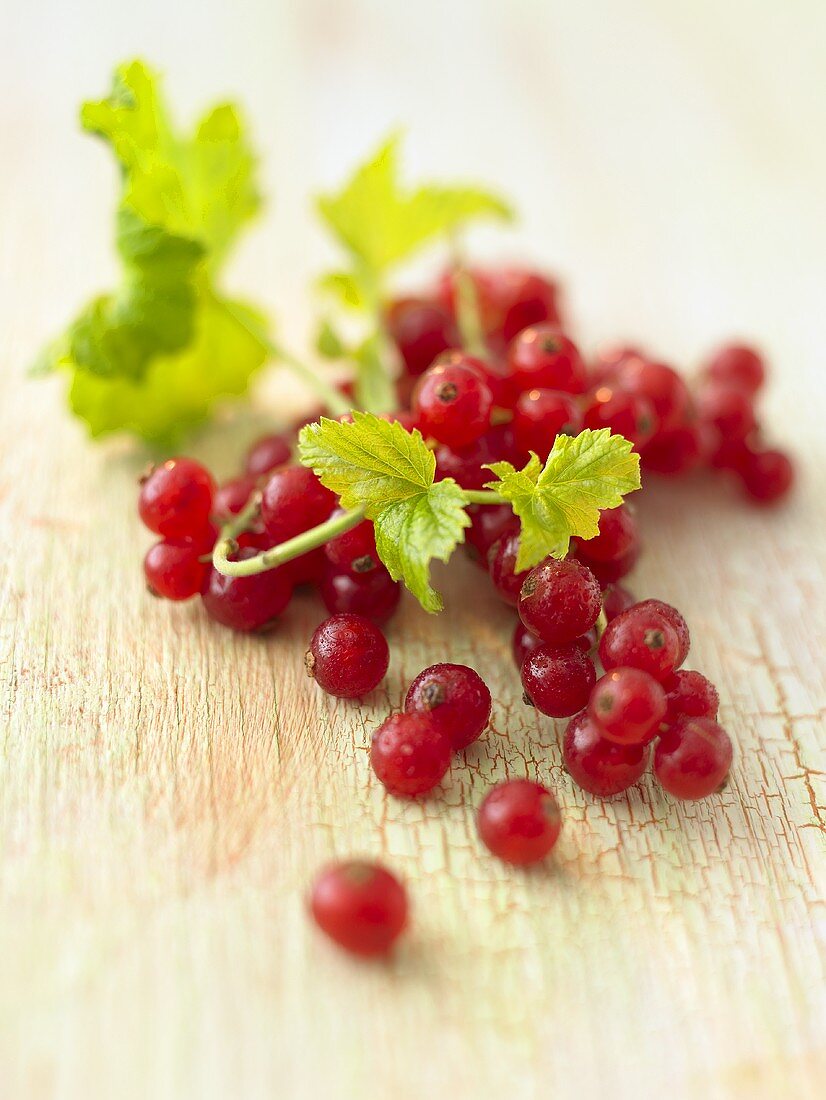 Rote Johannisbeeren mit Blättern auf Holzuntergrund