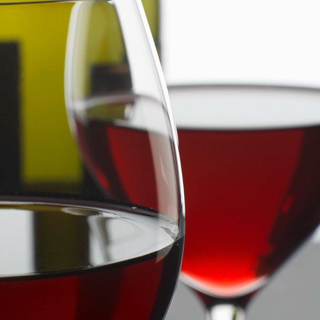 Two glasses of red wine in front of bottle (close-up)