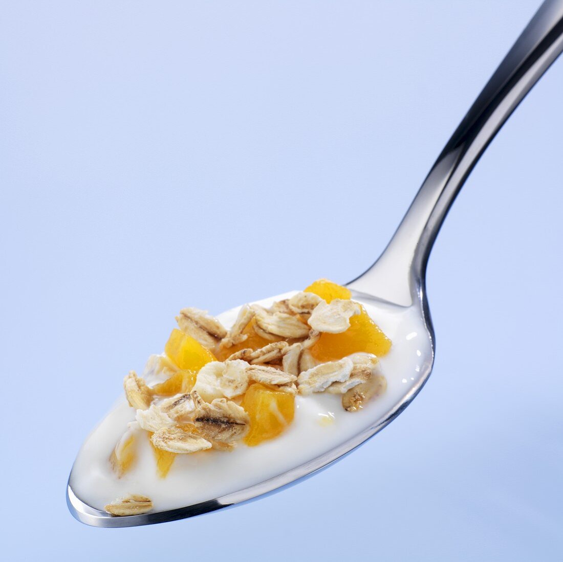 A spoonful of yoghurt with peach and muesli