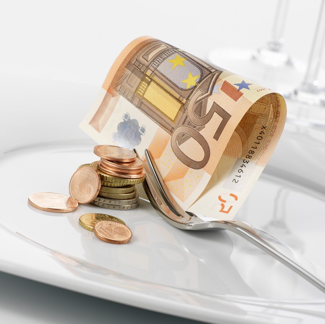 Euro notes and coins on plate with fork