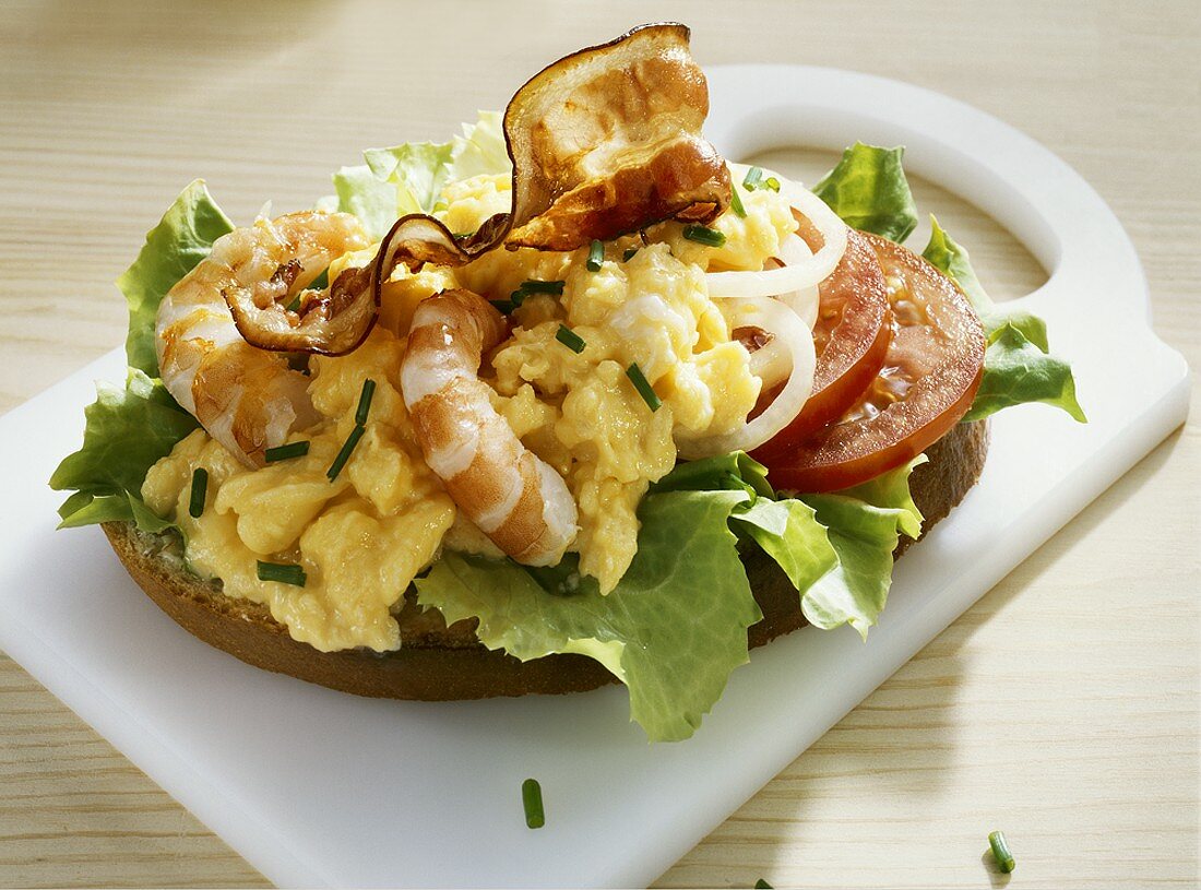 Bread topped with scrambled egg, prawns, tomatoes & bacon
