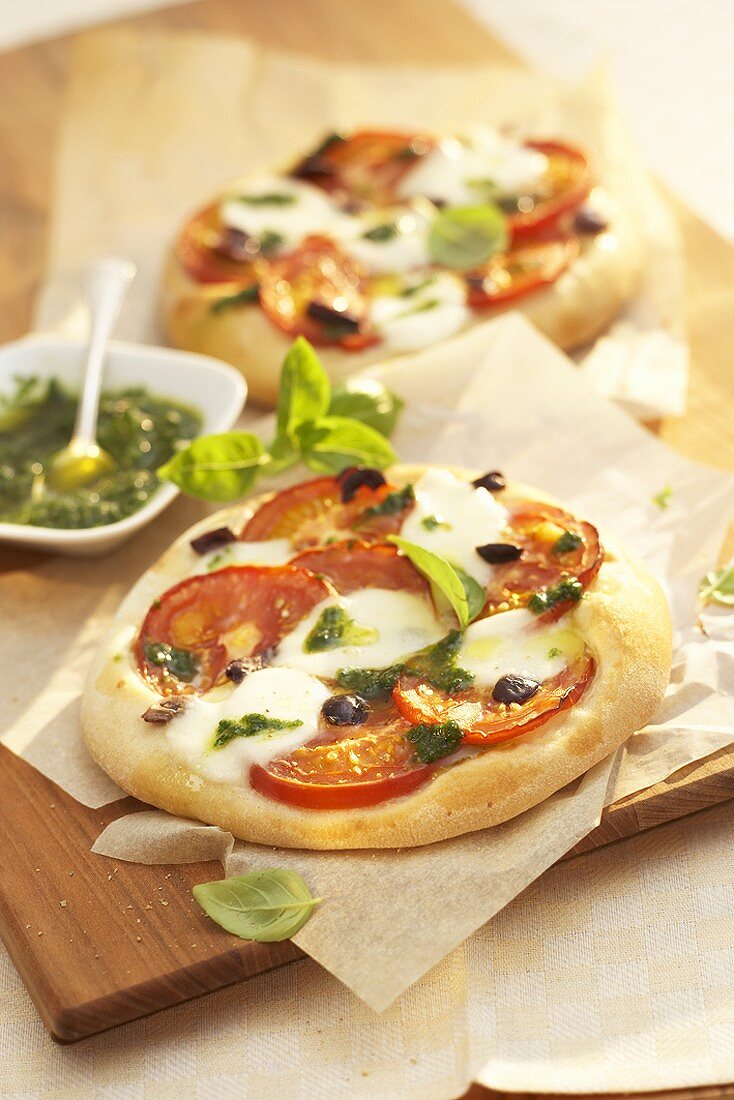 Mini-pizzas with tomato, mozzarella and pesto topping