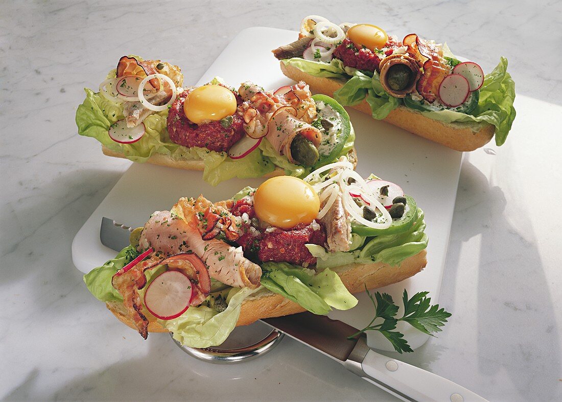 Baguettes topped with steak tartare, egg, sausage & salad