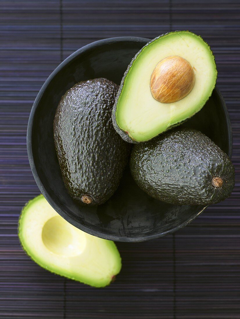 Avocados, whole and halved, in bowl