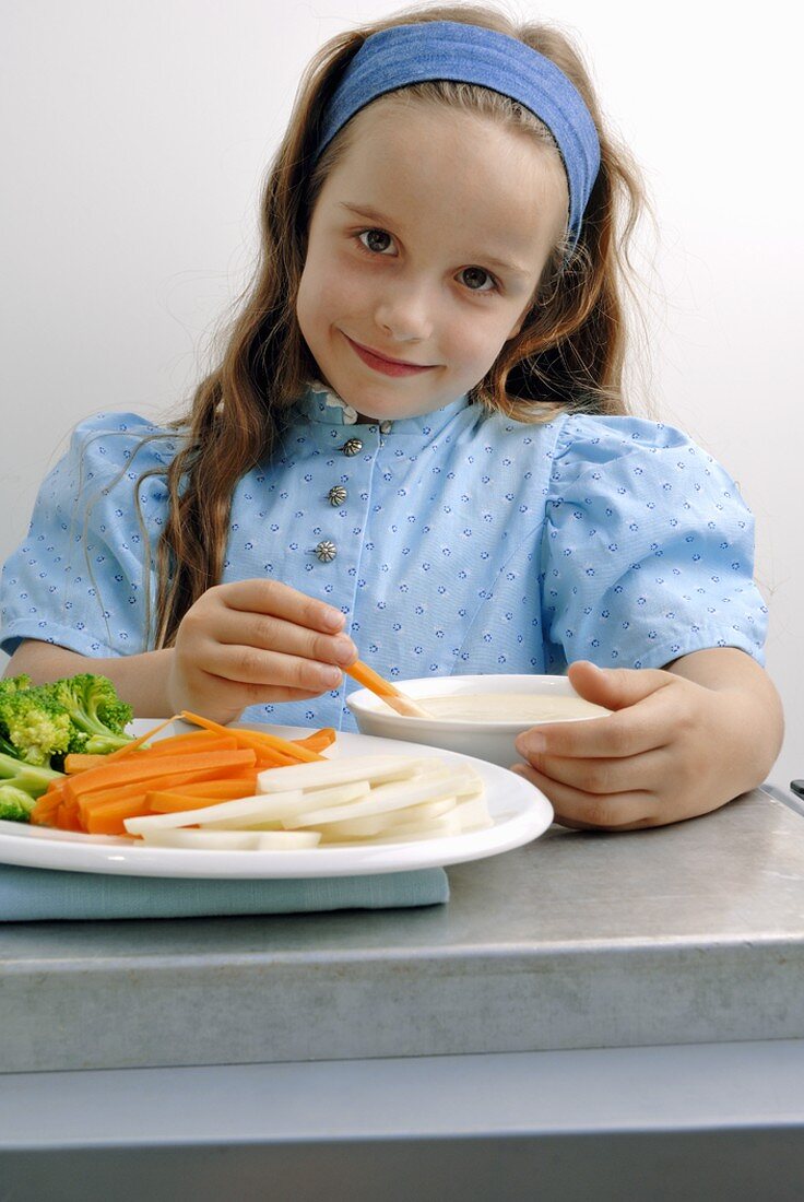 Girl eating raw vegetables with dip
