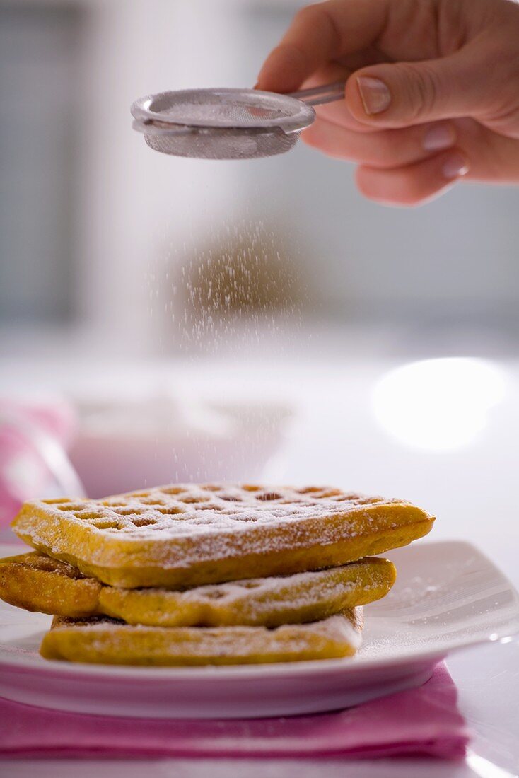 Sprinkling waffles with icing sugar