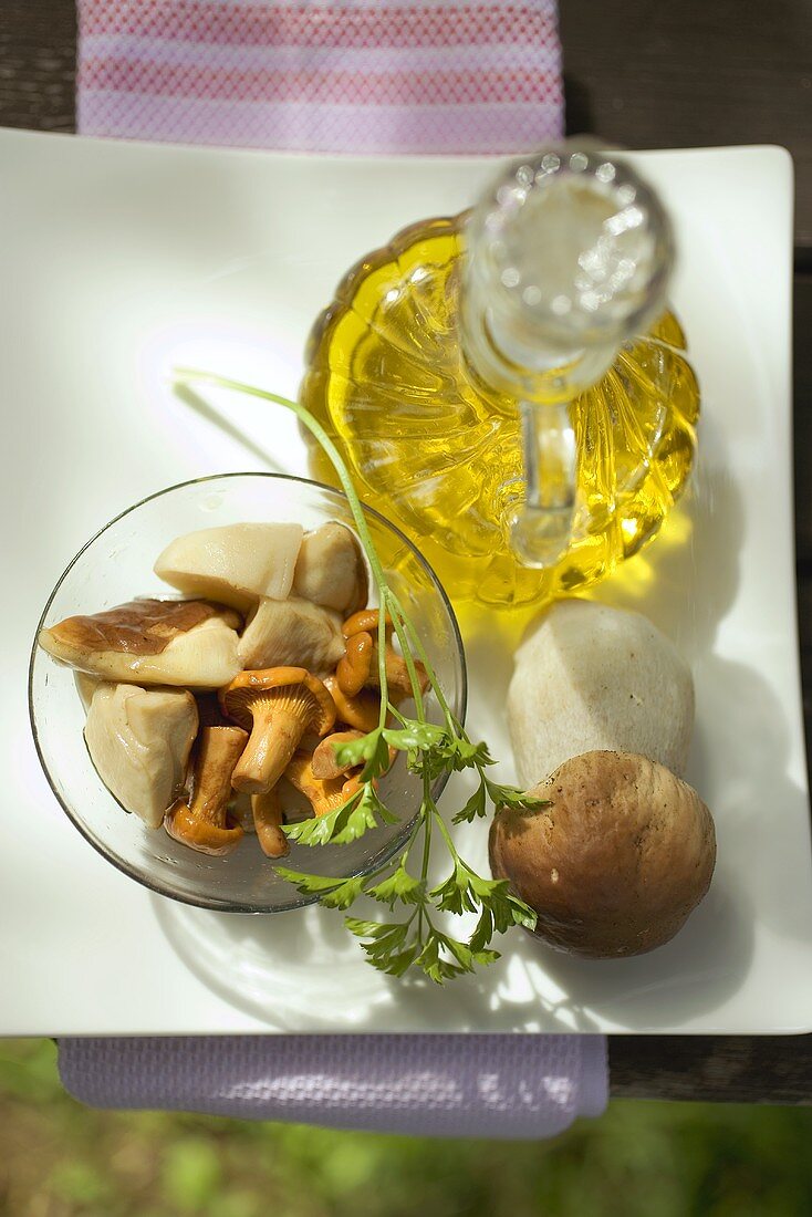 Eingelegte Pilze in Glasschale, Petersilie, Olivenöl